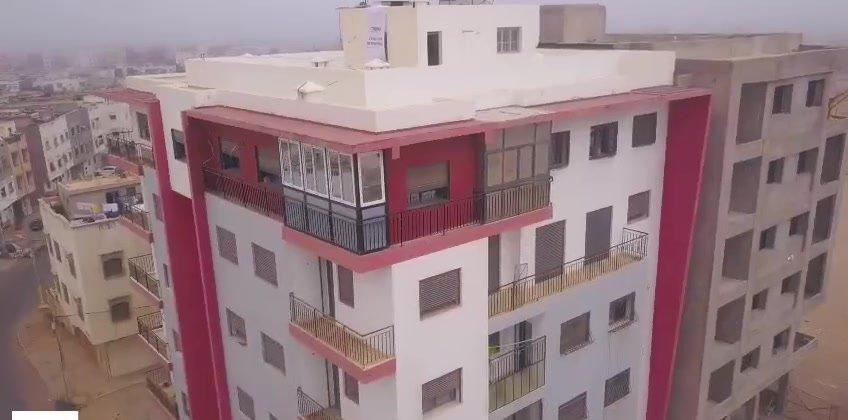 Immeuble terminé, façade blanche et bordeaux avec balcons